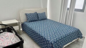 Ein Schlafzimmer mit einem Bett, einem Nachttisch und einem Babybett.
