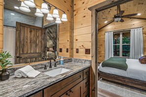 Een houten cabinestijl interieur met een badkamer, voorzien van een grote spiegel, een wastafel en een douche.