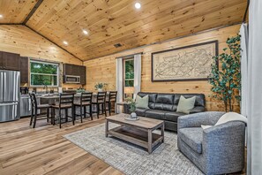 A wooden interior with a dining area, kitchen, and seating space. - Happy Chipmunk - Mountain Views, Hot Tub, Fire Pit & Game Room (Sevierville)