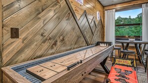 A billiards table with a wooden backdrop and a view of the outdoors. - Happy Chipmunk - Mountain Views, Hot Tub, Fire Pit & Game Room (Sevierville)