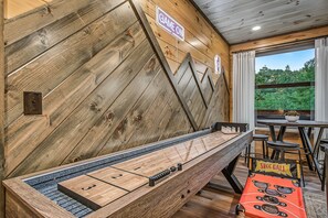 A billiards table with a wooden backdrop and a view of the outdoors. - Happy Chipmunk - Mountain Views, Hot Tub, Fire Pit & Game Room (Sevierville)