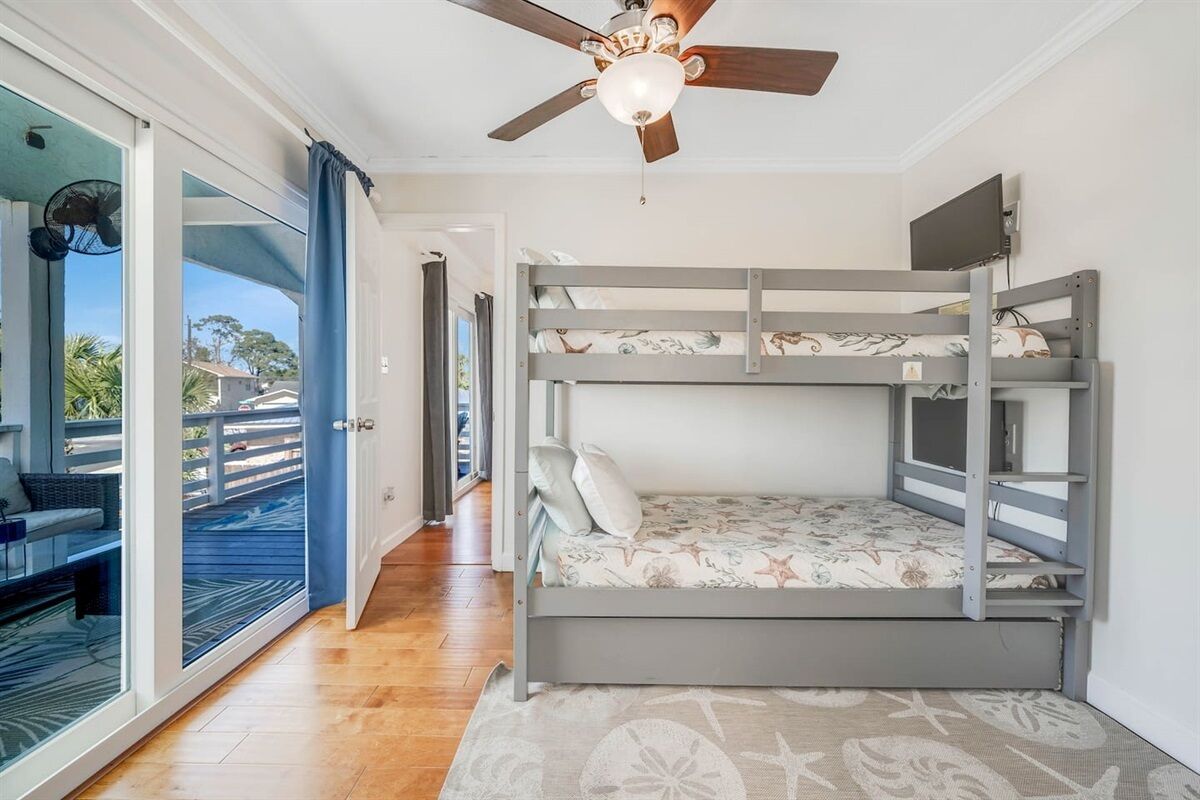 Een slaapkamer met een stapelbed, een ventilator, en uitzicht op de omgeving.