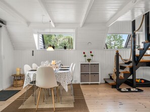 A dining area with a table set for four, a white ceiling, and a view of greenery outside. - "Ilsebeth" -  from the sea by Interhome (Hals)