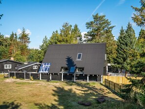 Ein modernes, zweigeschossiges Haus mit Satteldach, Solaranlage und umzäunter Garten.
