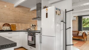 Une cuisine moderne avec des meubles blancs, un four encastré et un grand réfrigérateur.