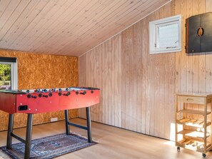 A room with a foosball table, a wooden cabinet, and a window. - "Ilsebeth" -  from the sea by Interhome (Hals)