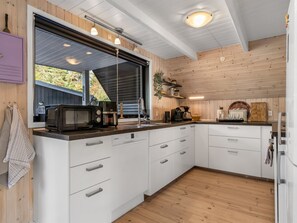 A modern kitchen with white cabinets, a microwave, and a coffee maker. - "Ilsebeth" -  from the sea by Interhome (Hals)