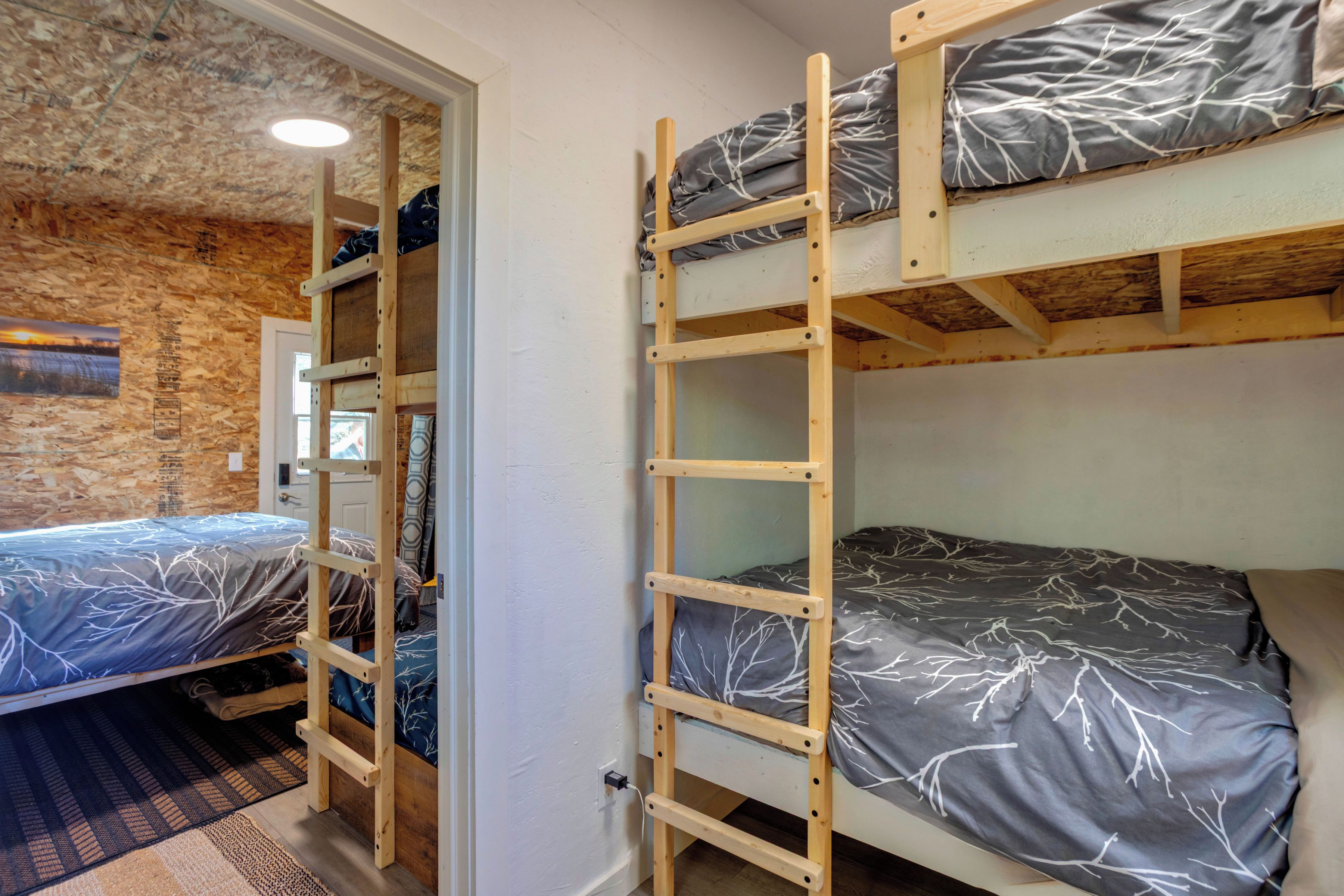 Une chambre avec un lit superposé, une échelle en bois, une porte et un mur à surface texturée.
