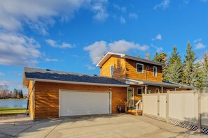 A two-story house with a garage, a covered porch, and a view of a lake.
