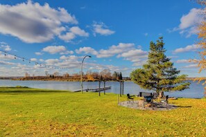 A lakeside park with a gazebo, picnic tables, and a tree.