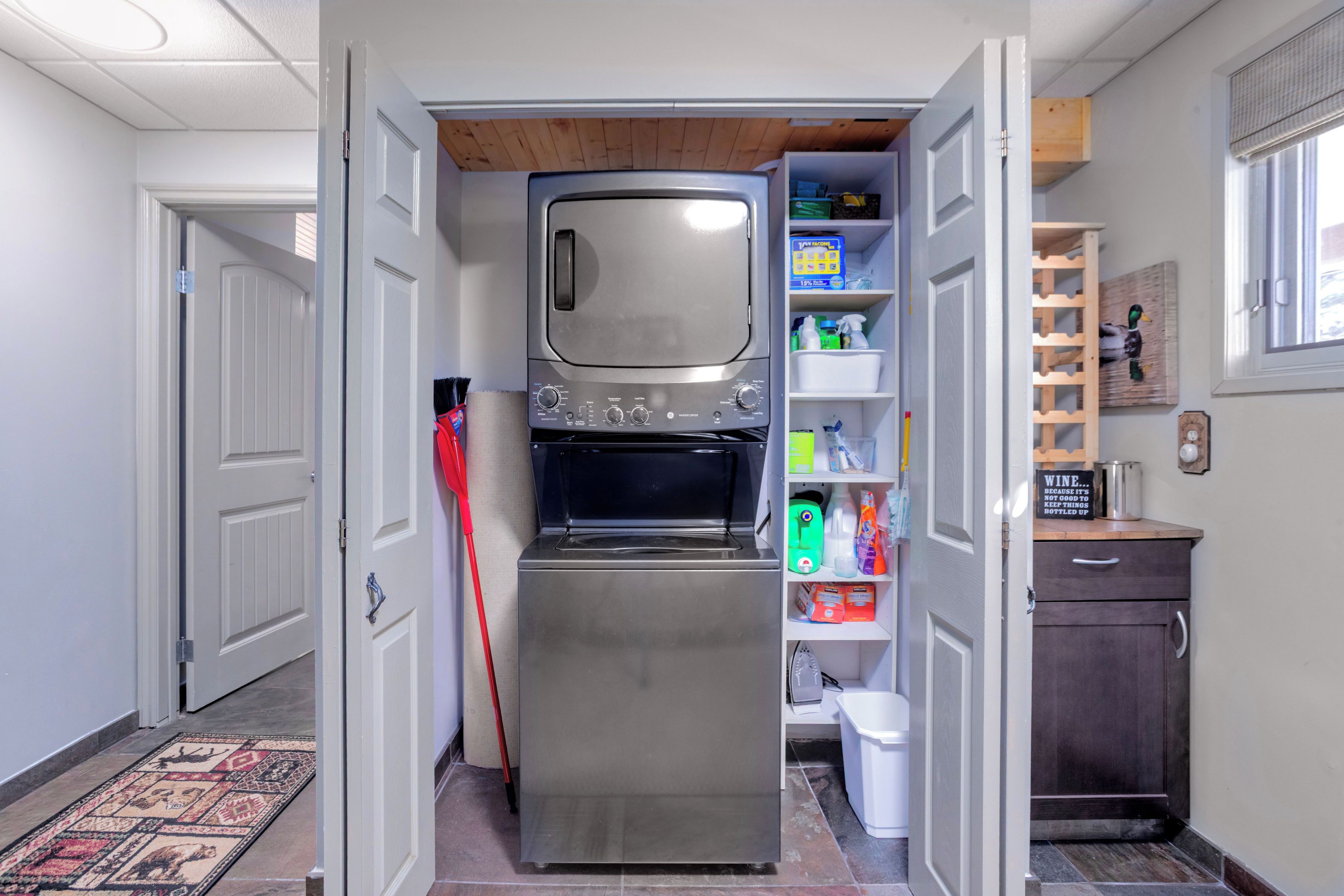 A compact kitchen with a built-in oven and microwave, a small pantry with storage shelves, and a wooden ceiling.
