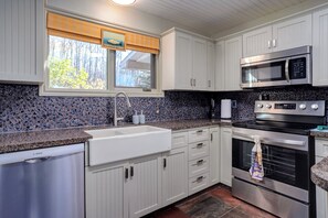 A kitchen with white cabinets, a stainless steel dishwasher, a microwave, and an oven.