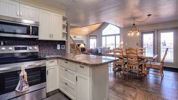 A modern kitchen with white cabinetry, a built-in microwave, and a granite countertop.
