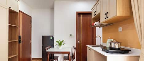 Una cocina compacta con una mesa de comedor, sillas, refrigerador y estufa.