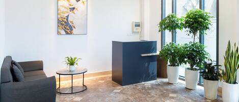A spacious lobby with a reception desk, seating area, and large windows.