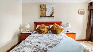 A bedroom with a bed, two nightstands, a wooden headboard, a decorative wall piece, and a night lamp on each side. - Romito | Accommodations for 5 people with parking, 5 minutes from Mall del Alto and 12 minutes from the Historic Center (Cuenca)