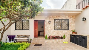 A residential property with a stone facade, a wooden bench, a small garden, and a metal gate. - Romito | Accommodations for 5 people with parking, 5 minutes from Mall del Alto and 12 minutes from the Historic Center (Cuenca)