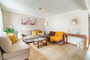 Uma sala de estar com um sofá, uma mesa de centro, uma luminária e um espelho decorativo.