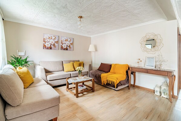 A living room with a sofa, a coffee table, a lamp, and a decorative mirror.