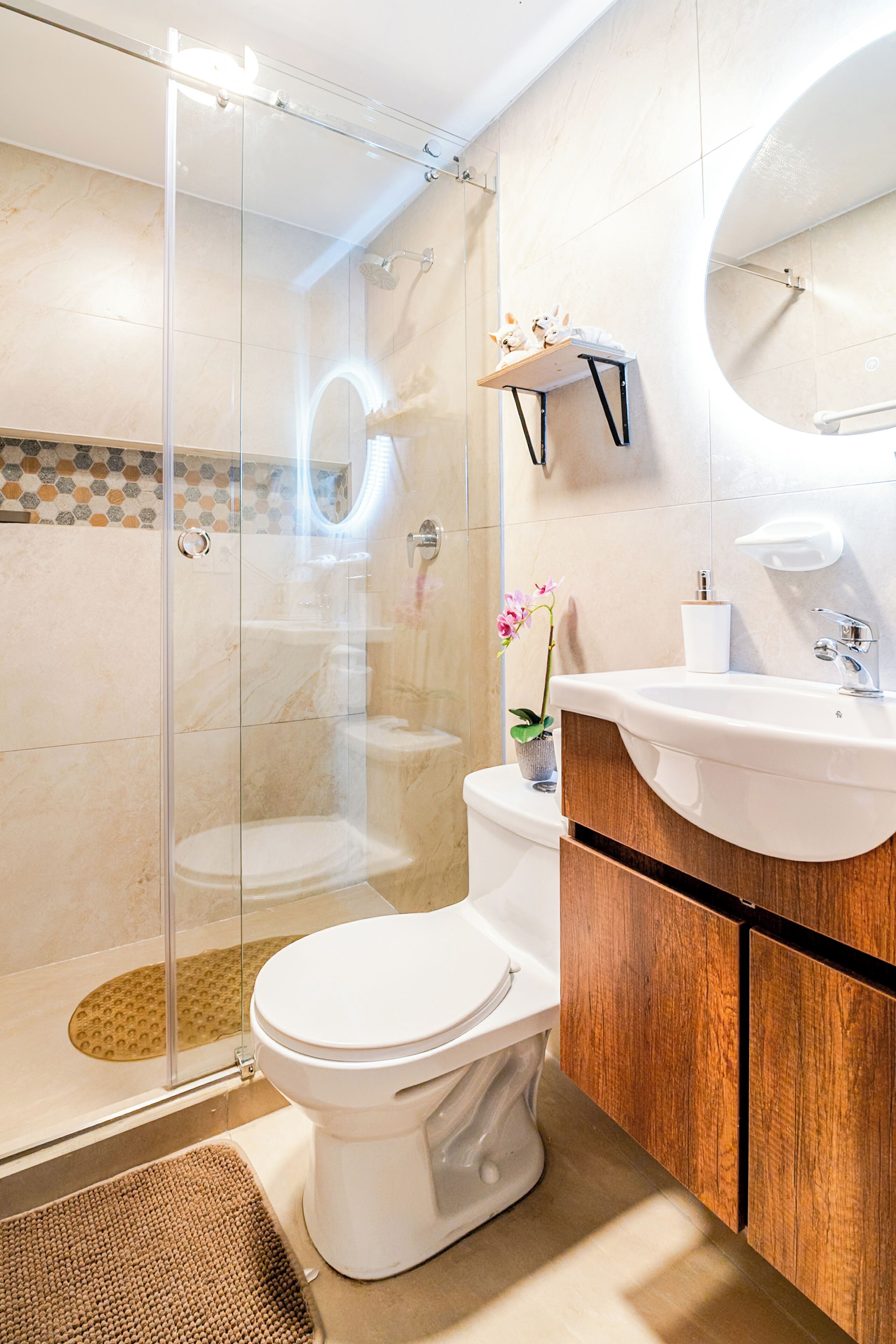 Un baño moderno con ducha de vidrio, inodoro, lavabo y espejo.