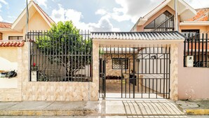 A gated entrance to a residential property with a tiled roof, a stone wall, and a metal gate. - Romito | Accommodations for 5 people with parking, 5 minutes from Mall del Alto and 12 minutes from the Historic Center (Cuenca)