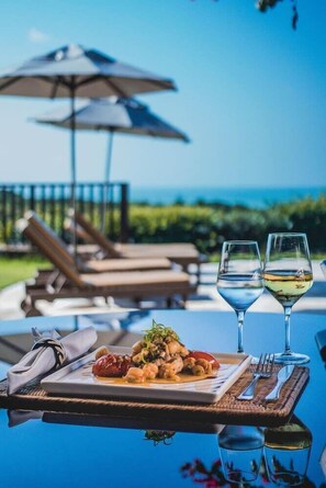 Una mesa de comedor con un plato de comida, dos copas de vino y una servilleta.