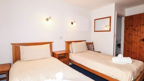 A hotel room with two beds, wooden headboards, bedside tables, a mirror, and a wooden wardrobe. - IRIS AT STANCOMBE MANOR, pet friendly, with pool in Chillington (Kingsbridge)