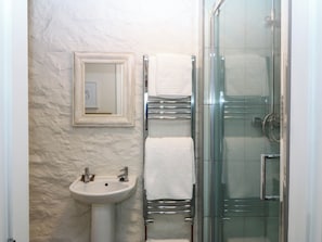 A bathroom with a glass shower enclosure, a white sink, and a towel rack with white towels. - LITTLE OAK, pet friendly, character holiday cottage in Tal-Y-Bont (Conwy)
