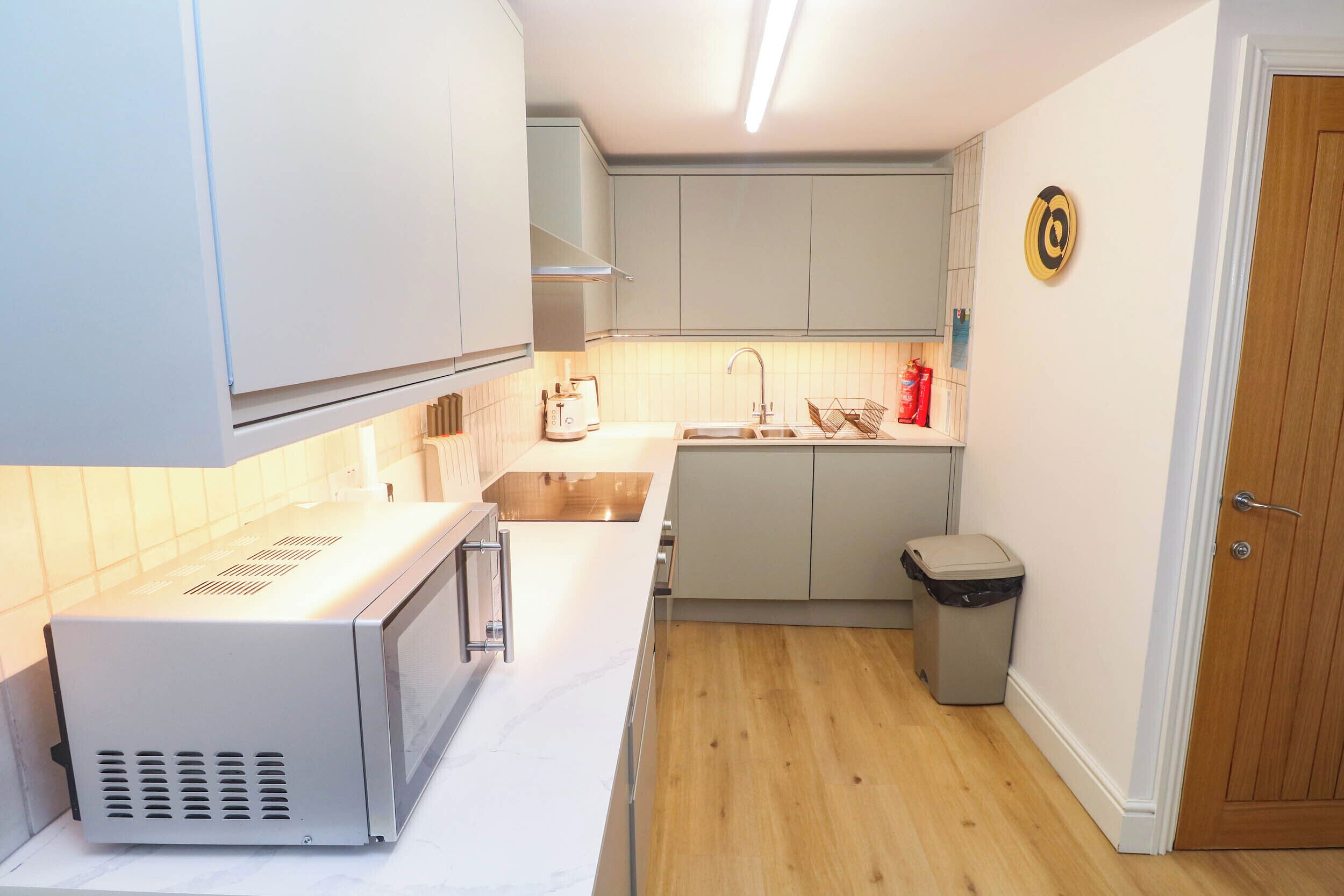 A compact kitchen with white cabinets, a stainless steel sink, and a microwave.
