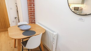 A small dining area with a wooden table, a white chair, a blue bowl, and a white radiator.
