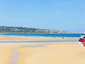 Une plage avec un ciel dégagé, un drapeau et une ville lointaine.