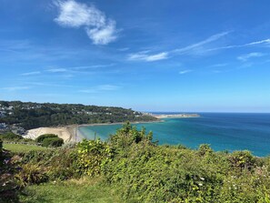 A coastal landscape with a beach, ocean, and a hill with vegetation. - INFINITE HORIZON, romantic, country holiday cottage in Carbis Bay (St. Ives)