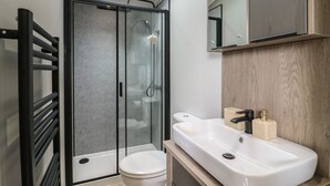 Ein modernes Badezimmer mit Duschkabine aus Glas, einer weißen Toilette und einem Waschbecken mit Holzablagefläche.