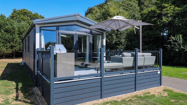 Eine moderne Terrassengrundstück mit Glasumrandung, einem Grill und einer Sitzgruppe.