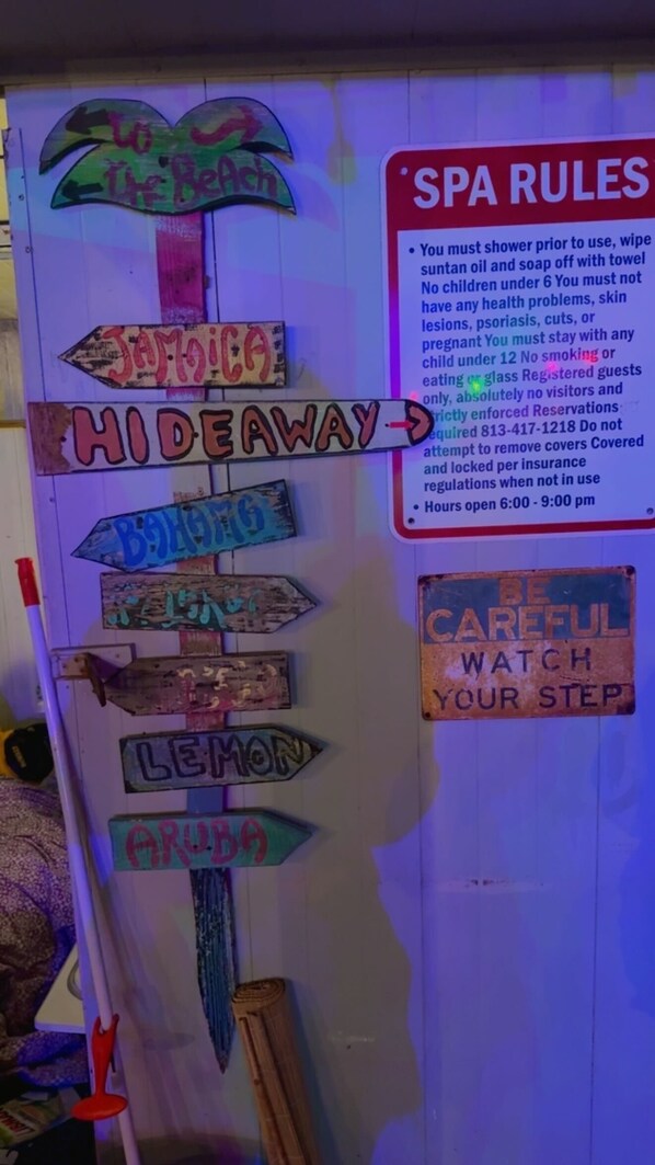 A wall with multiple directional signs and a list of spa rules.