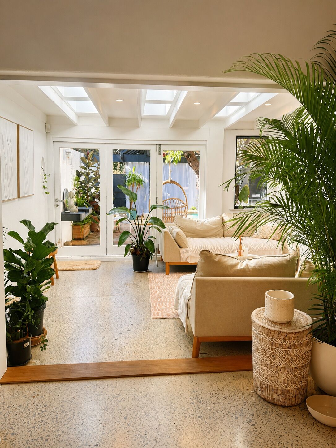 A modern living room with a sofa, a coffee table, and potted plants.