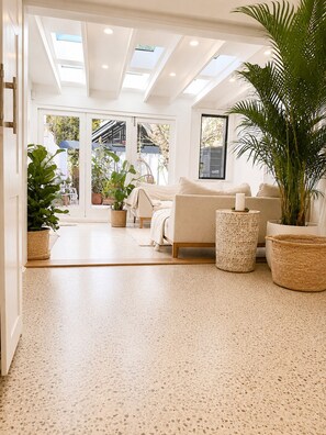 Uma sala de estar espaçosa com sofá, mesa de centro e plantas em vasos.