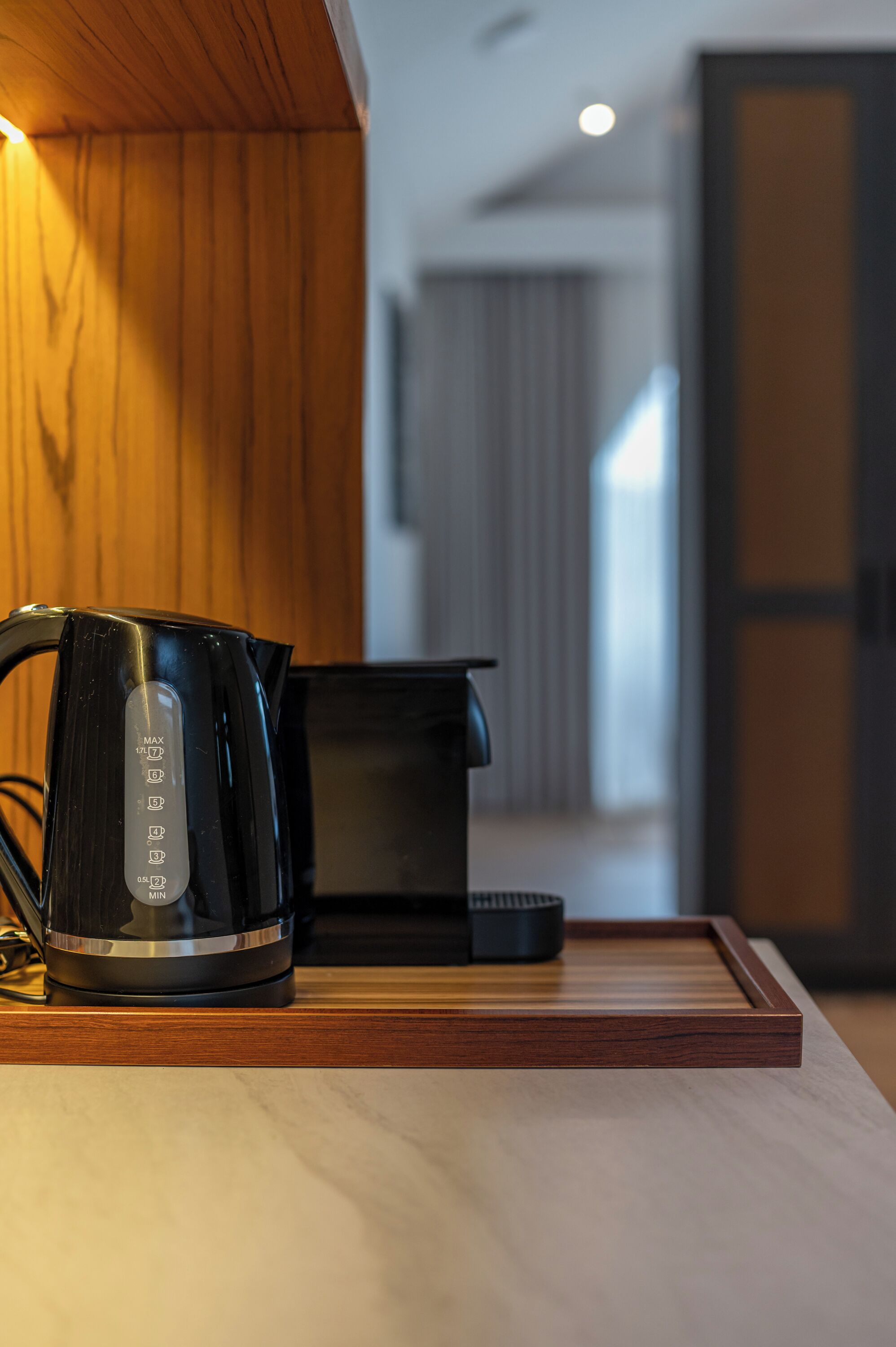 A modern kitchen with a coffee maker and a kettle on a wooden countertop.