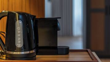 A modern kitchen with a coffee maker and a kettle on a wooden countertop.