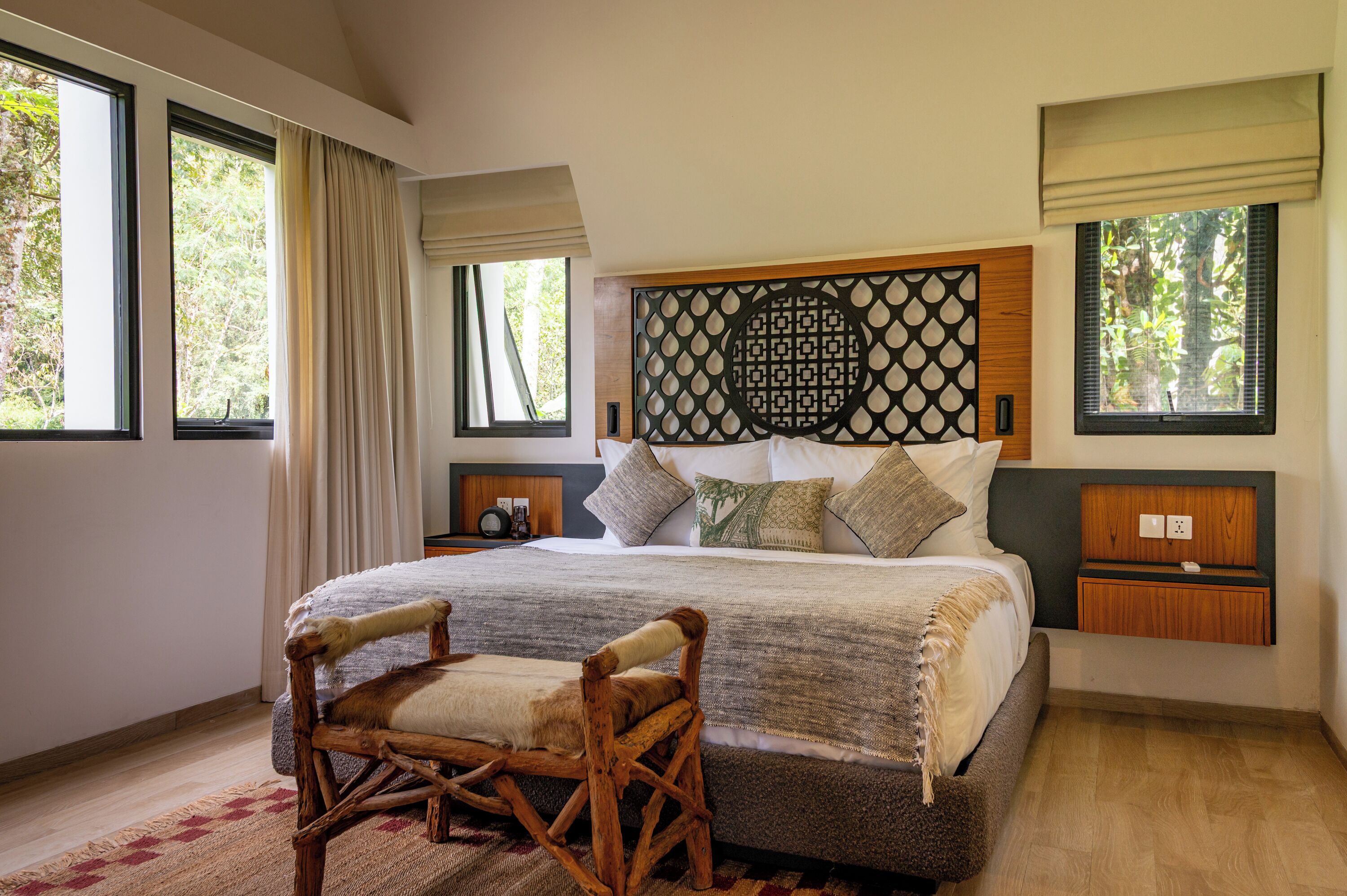 A bedroom with a large bed, a wooden chair, and a decorative headboard.