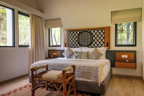 A bedroom with a large bed, a wooden chair, and a decorative headboard.