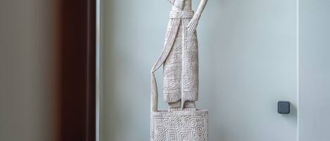 A white statue of a figure with a headdress, standing on a pedestal with geometric patterns.