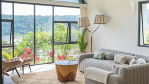 A modern living room with a large window, a sofa, a coffee table, and a floor lamp.