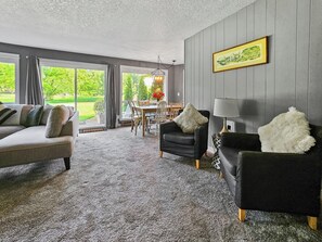 A living room with a grey sofa, a black armchair, and a dining table with chairs. - Mt Hood Condo Near Skiing & Golf Hawaiian-Inspired (Mount Hood Village)