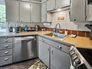 A compact kitchen with a dishwasher, sink, and stove. - Mt Hood Condo Near Skiing & Golf Hawaiian-Inspired (Mount Hood Village)
