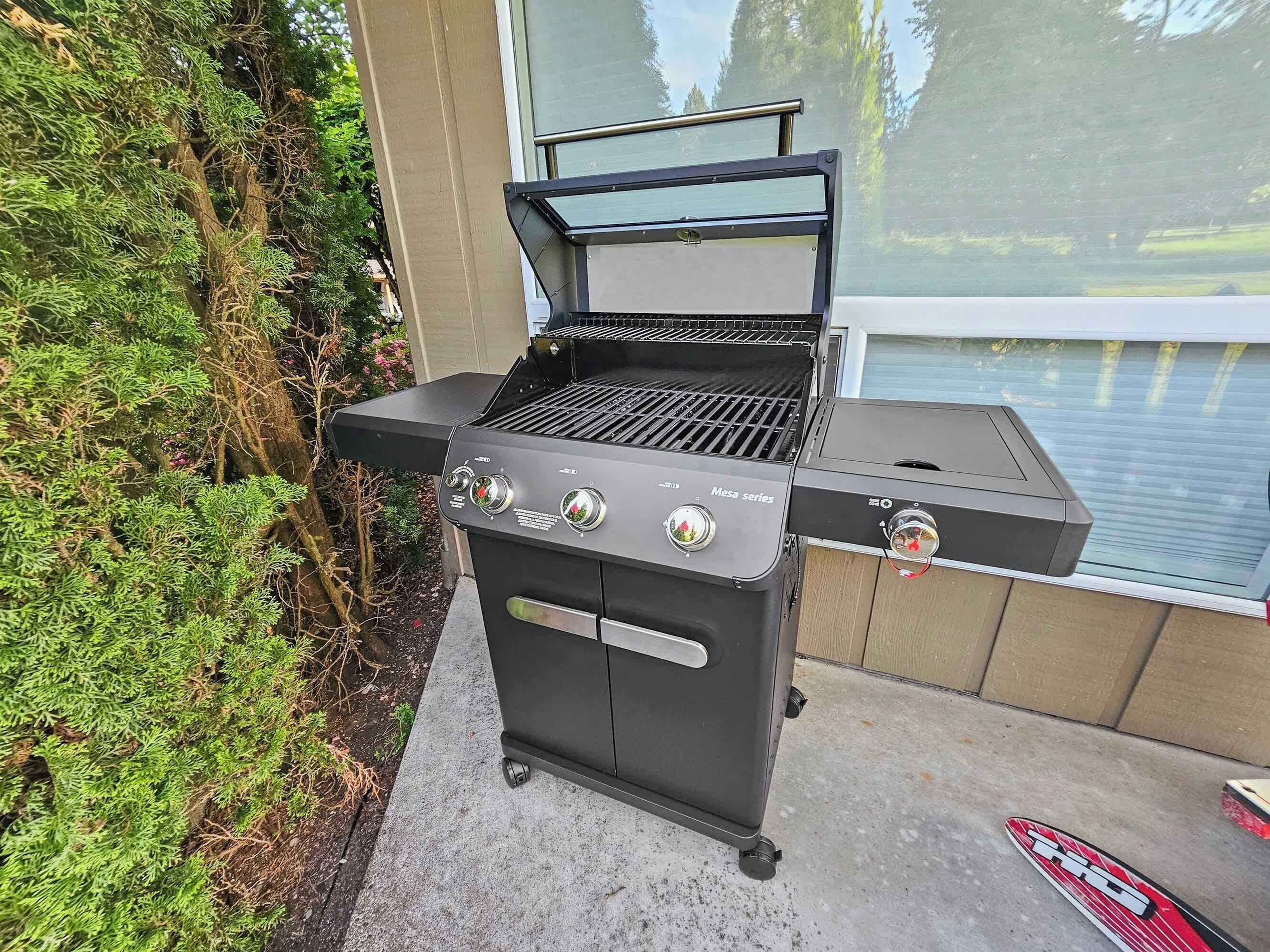 A black outdoor grill with a side burner, a digital display, and a control panel.