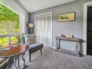A room with a window, a chair, a table, a lamp, a fireplace, and a framed picture on the wall. - Mt Hood Condo Near Skiing & Golf Hawaiian-Inspired (Mount Hood Village)