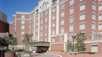 A multi-story hotel with a brick facade, large windows, and a central courtyard with a covered seating area.