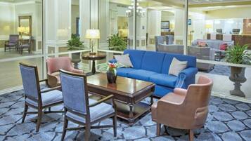 A lobby with a blue sofa, two armchairs, a coffee table, and a mirror reflecting the room.