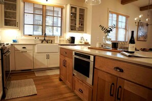 Eine Küche mit Holzausstattung, einem Edelstahlbackofen und einem Fenster mit Jalousien.